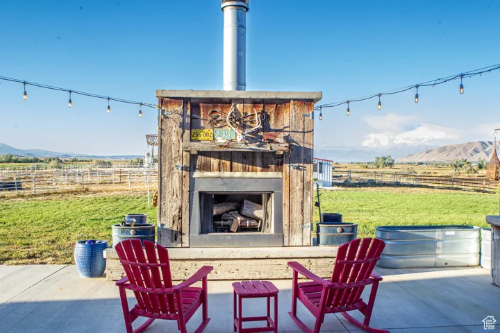 View of patio featuring an outdoor fireplace, a mountain view, and a view of rural / pastoral area