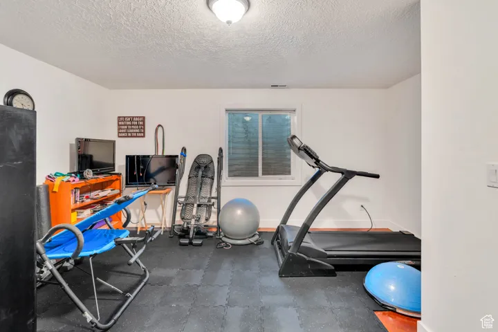 Workout area featuring a textured ceiling and baseboards