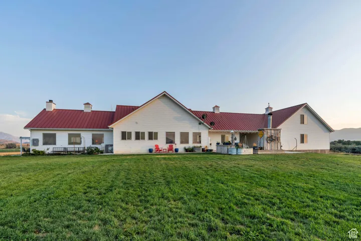 Back of property featuring a metal roof, a chimney, a patio area, a yard, and a standing seam roof