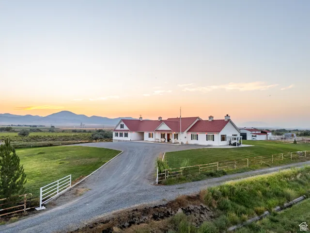 View of front of home with driveway, a chimney, and a view of rural / pastoral area