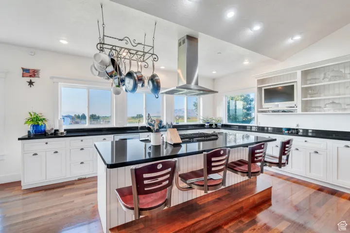 Kitchen featuring light wood-style floors, a breakfast bar, healthy amount of natural light, recessed lighting, and lofted ceiling