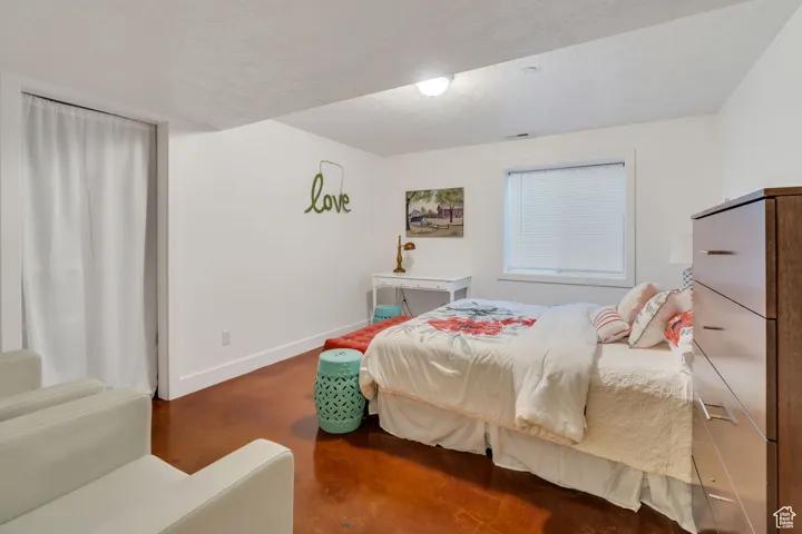 Bedroom with a textured ceiling and concrete flooring