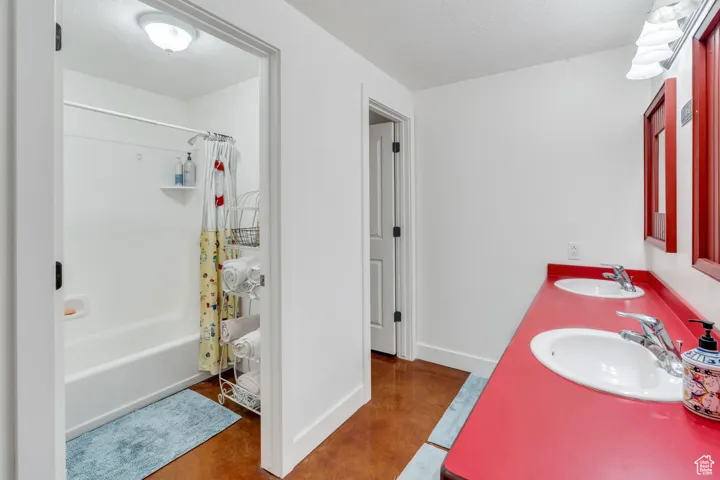 Bathroom with shower / tub combo, double vanity, concrete flooring, and a textured ceiling
