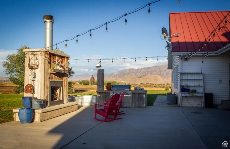 View of patio / terrace featuring a mountain view, an outdoor fireplace, and a grill