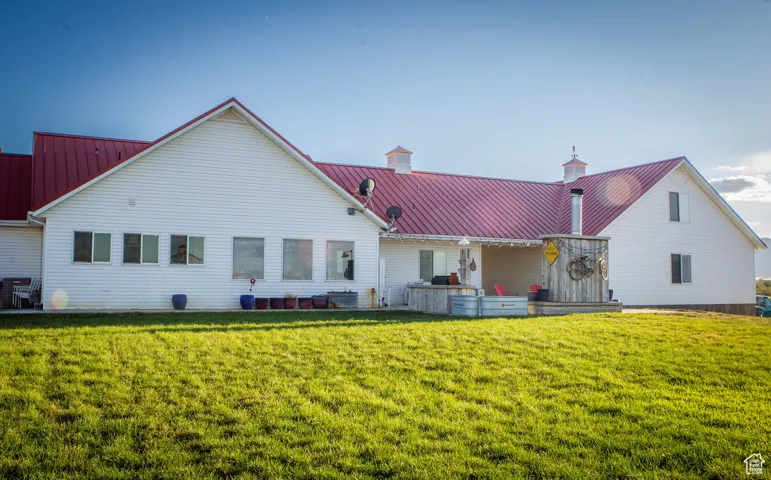 Rear view of house featuring a metal roof, a lawn, and a patio area