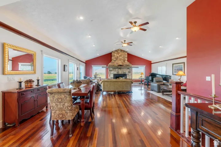 Dining space featuring vaulted ceiling, dark wood-style flooring, a fireplace, and a ceiling fan