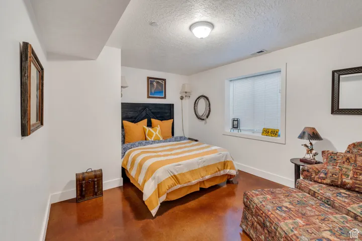 Bedroom featuring a textured ceiling and finished concrete floors