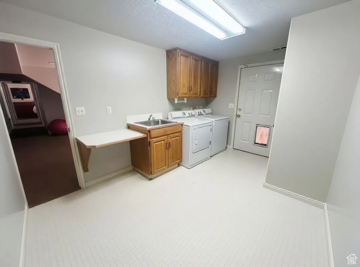 Laundry area with washer and dryer, a textured ceiling, and cabinet space