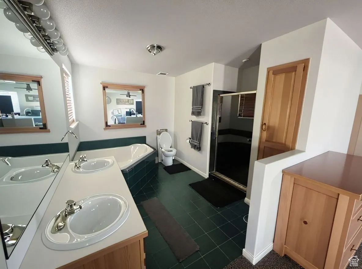 Bathroom with a shower stall, double vanity, dark tile patterned floors, and a garden tub