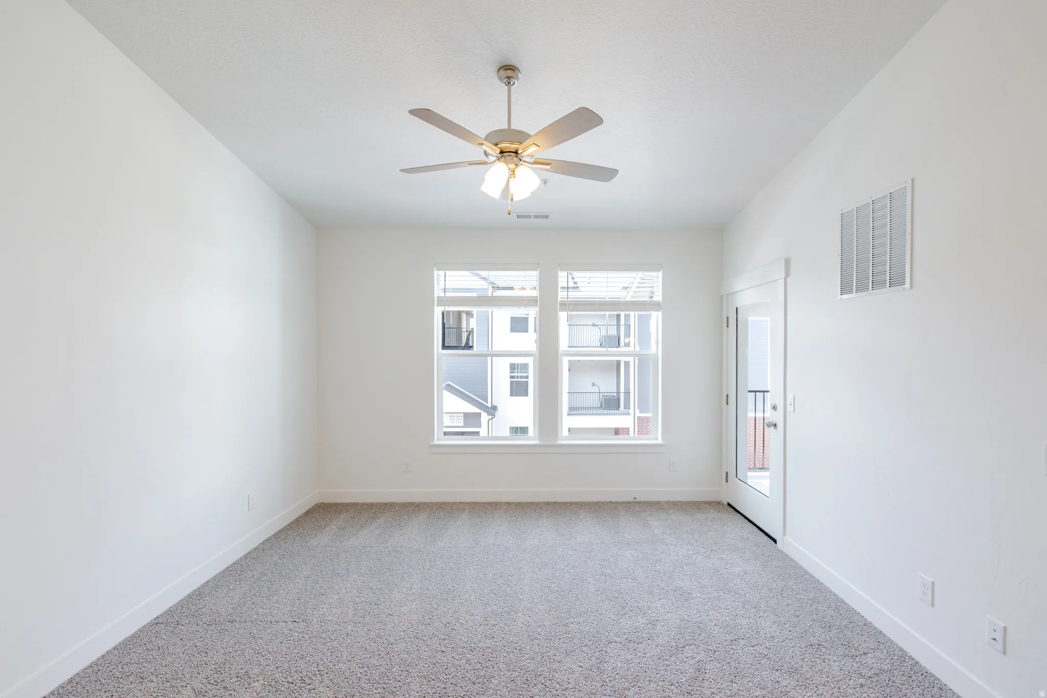 Empty room featuring light carpet and ceiling fan