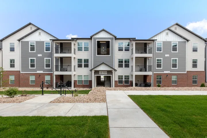 Multi-story building exterior featuring a combination of brick, horizontal siding, and vertical paneling