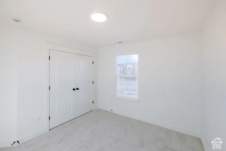 Plush carpet flooring, white walls, double panel doors, and a single window