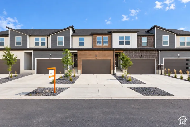 Townhome exterior featuring varied siding materials, attached garages, and concrete driveways