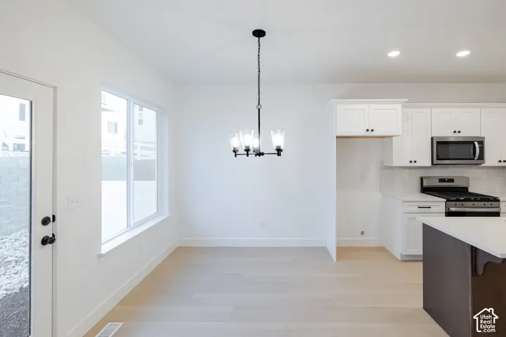 Bright dining area featuring wood-finish flooring, a contemporary chandelier, and large windows