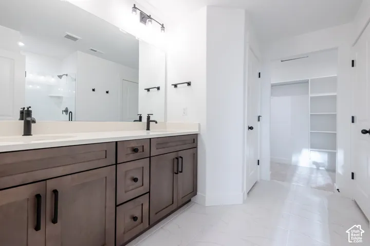 Dual sink vanity with dark wood-finish cabinetry, light countertop, and matte black fixtures