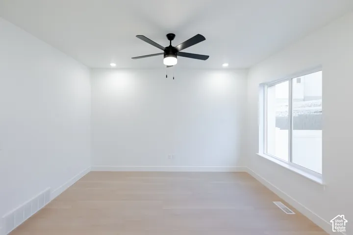 Light wood-finish flooring, recessed ceiling lighting, a modern ceiling fan, and a large window