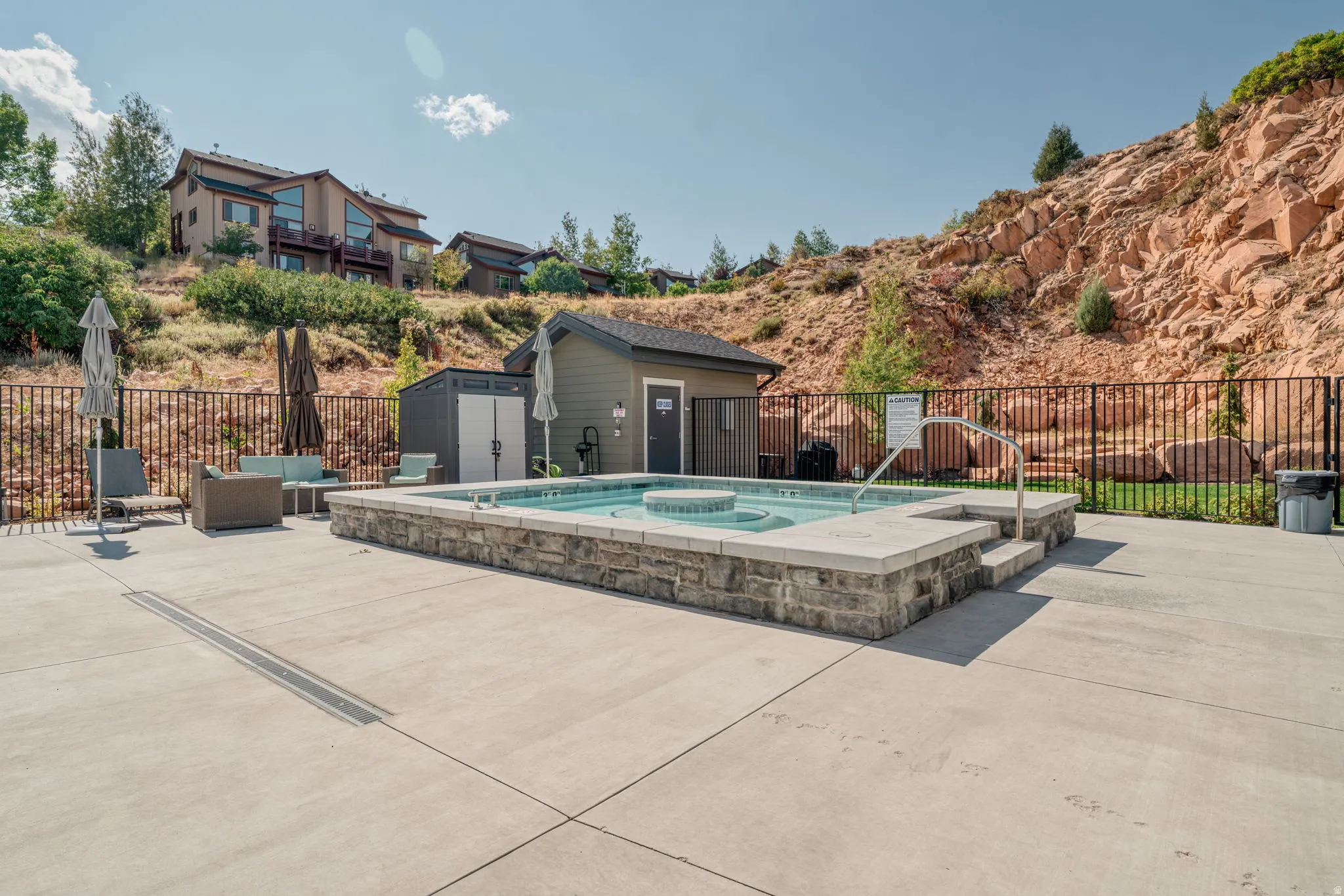 Stone-clad hot tub with integrated seating, surrounded by a concrete patio
