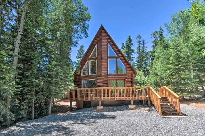 Rear view of house featuring log exterior, a wooden deck, and stairs