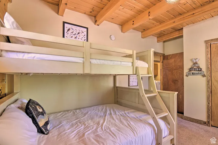 Carpeted bedroom featuring a wood ceiling with exposed beams