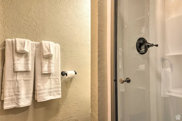 Full bath featuring a textured wall and a stall shower