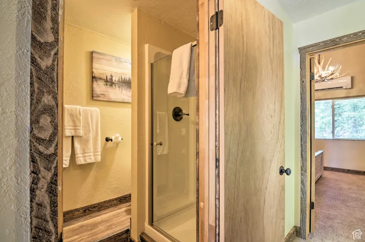 Full bath with a textured wall and a shower stall