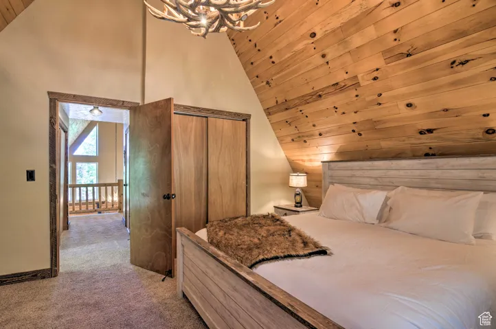 Bedroom featuring light colored carpet, wooden ceiling, a closet, and high vaulted ceiling