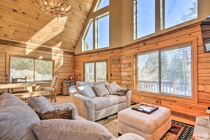 Living room with wood walls, wood finished floors, healthy amount of natural light, wood ceiling, and high vaulted ceiling