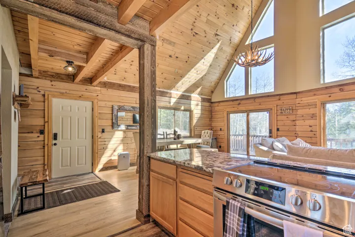 Kitchen with wood walls, electric range, dark stone counters, plenty of natural light, and light wood-style floors