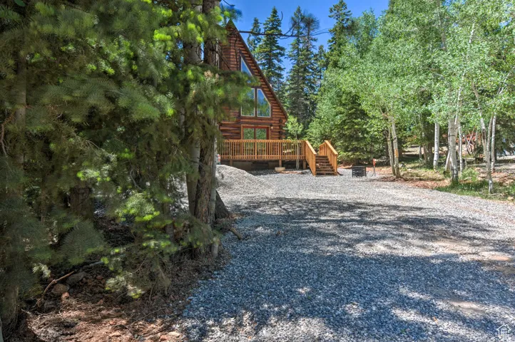 View of property exterior featuring log siding, a deck, and gravel driveway