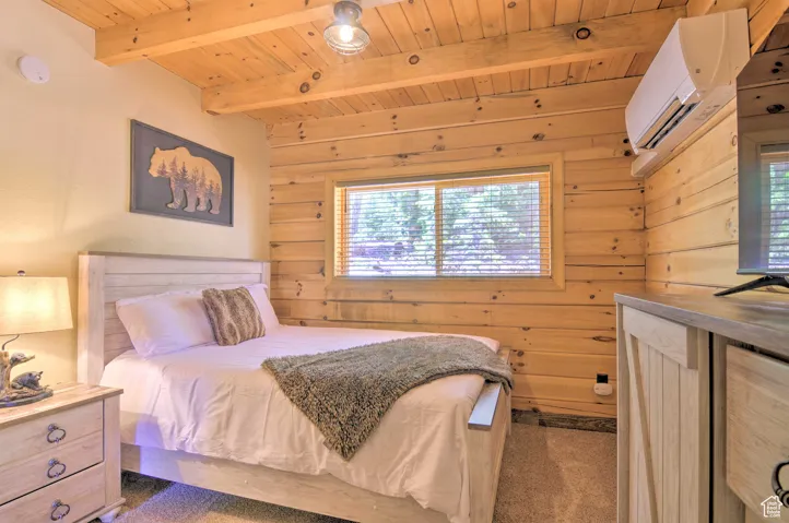 Carpeted bedroom featuring a wood ceiling with exposed beams, wooden walls, and a wall mounted air conditioner