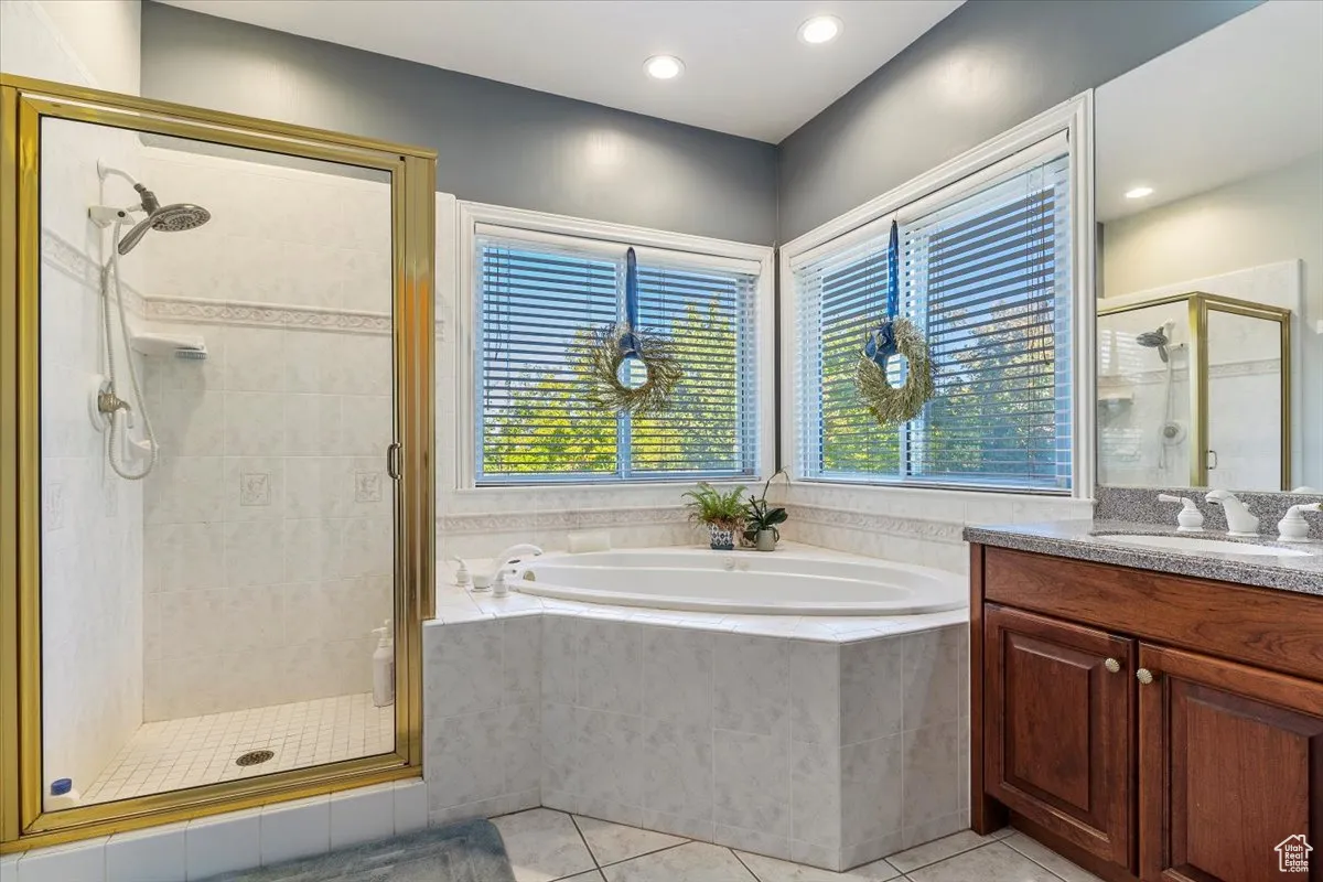 Bathroom with a shower stall, light tile patterned flooring, a garden tub, vanity, and recessed lighting