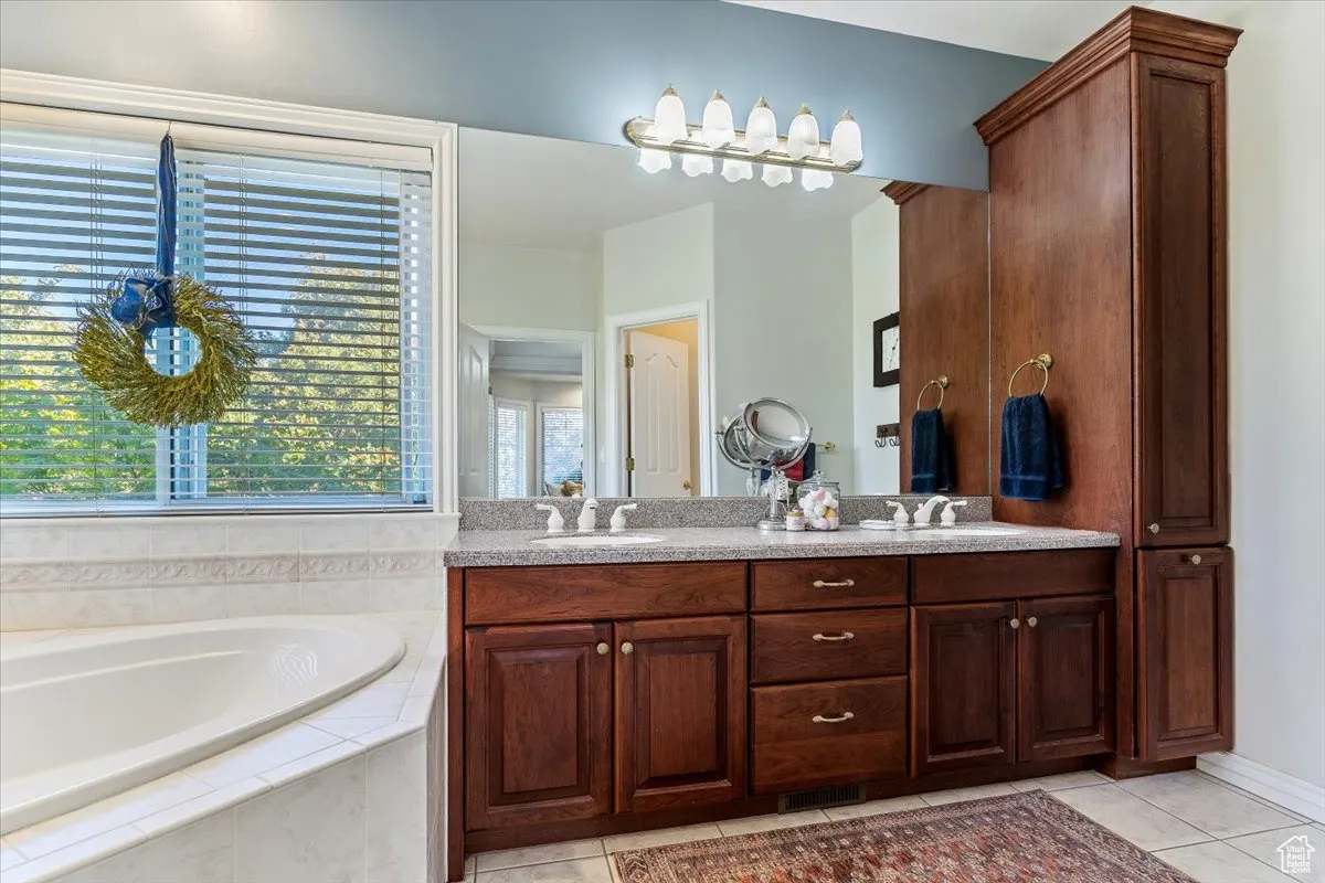 Bathroom with double vanity, a bath, and light tile patterned floors