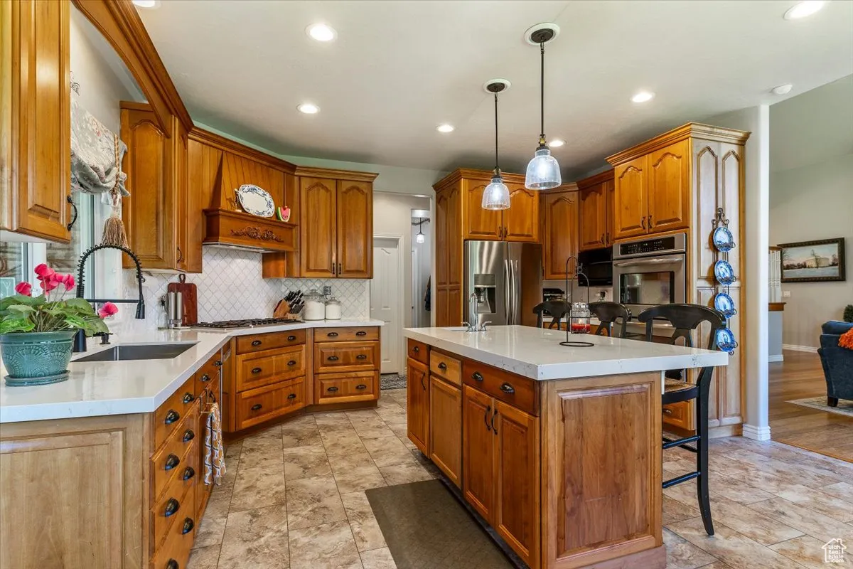 Kitchen with brown cabinets, a breakfast bar area, a center island with sink, and recessed lighting