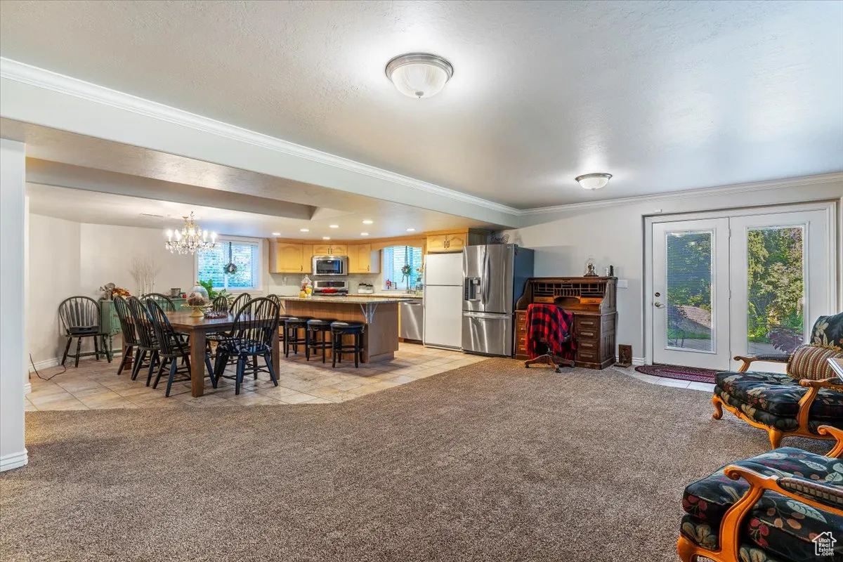 Dining room with light colored carpet, crown molding, a chandelier, a textured ceiling, and light tile patterned floors
