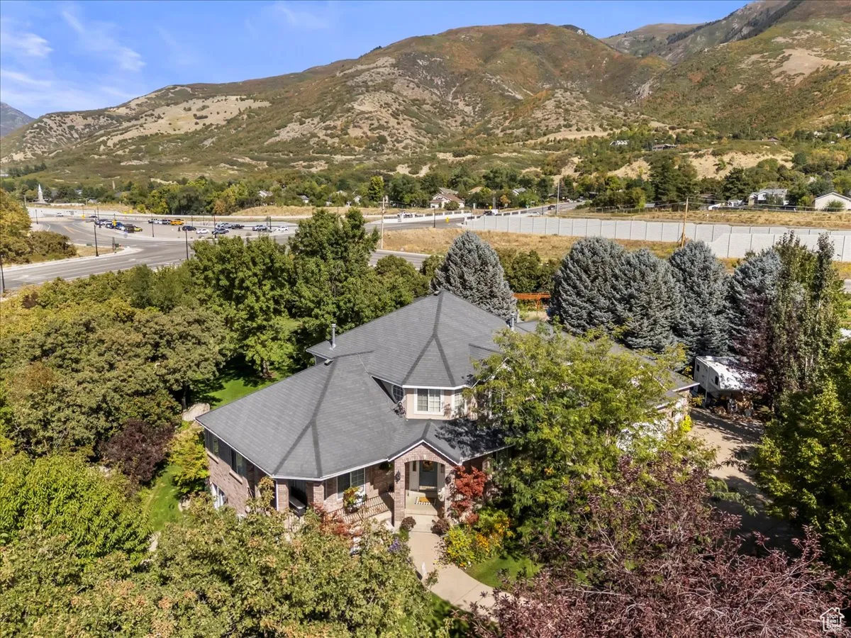 Aerial view of property and surrounding area with a mountainous background and a tree filled landscape