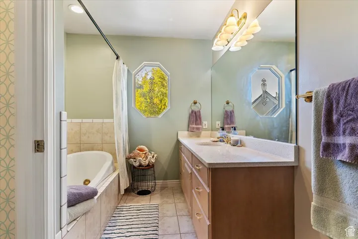 Bathroom featuring vanity, a whirlpool tub, and light tile patterned floors