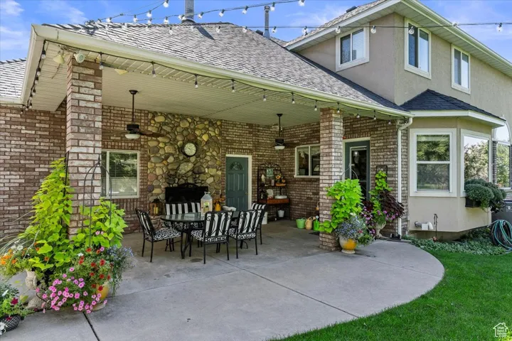 Back of property with a patio, stucco siding, brick siding, roof with shingles, and outdoor dining space