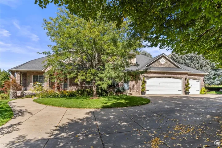 Obstructed view of property featuring concrete driveway, brick siding, a garage, covered porch, and a front lawn