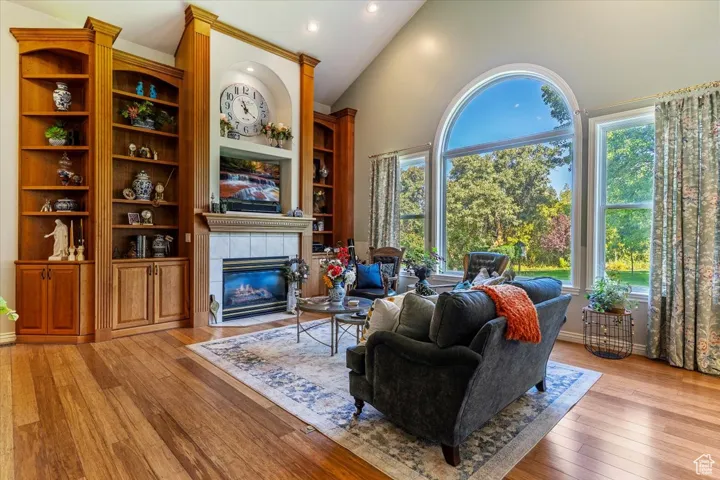 Living area with a fireplace, light wood-type flooring, recessed lighting, high vaulted ceiling, and built in shelves