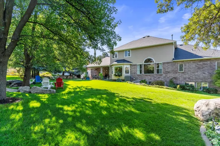 Rear view of property featuring a patio, a lawn, brick siding, and stucco siding