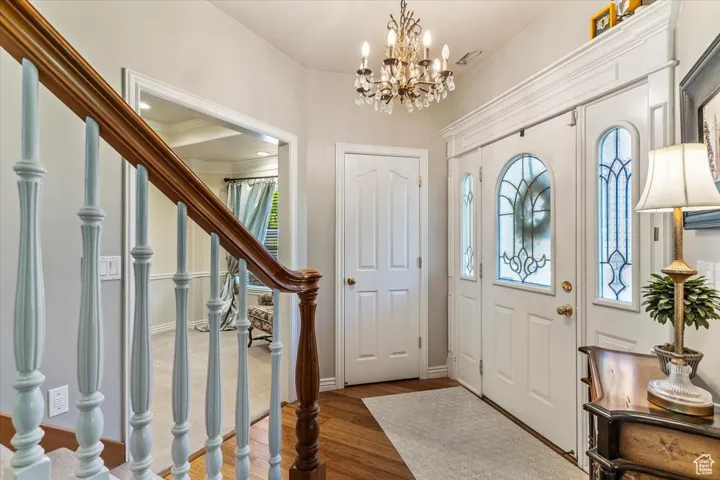 Foyer with stairs, wood finished floors, and a chandelier