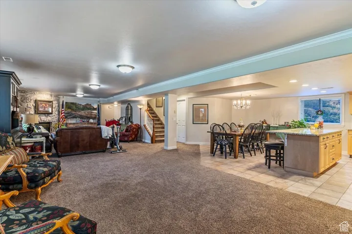 Living room featuring light colored carpet, stairway, light tile patterned floors, and ornamental molding