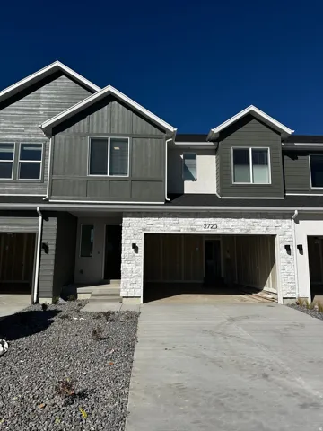View of front facade with stone siding, a garage, concrete driveway, a porch, and board and batten siding