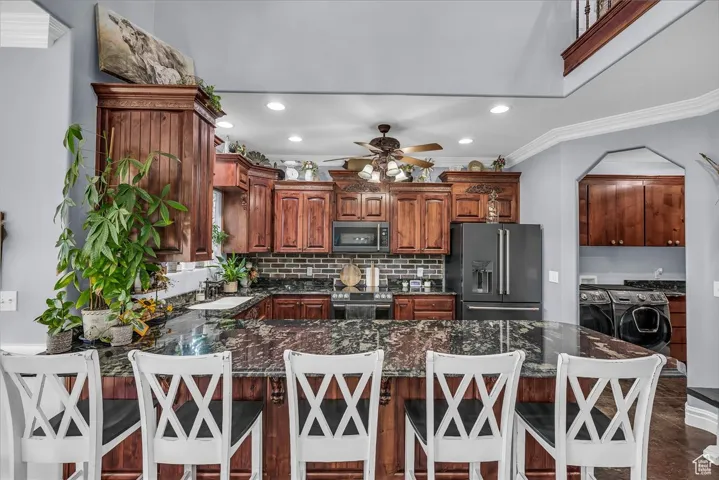 Kitchen with a peninsula, appliances with stainless steel finishes, tasteful backsplash, dark stone countertops, and recessed lighting