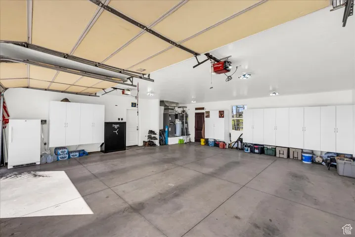 Garage with freestanding refrigerator and a garage door opener