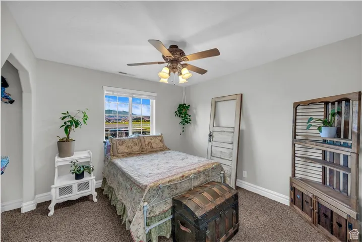 Bedroom with dark colored carpet and a ceiling fan