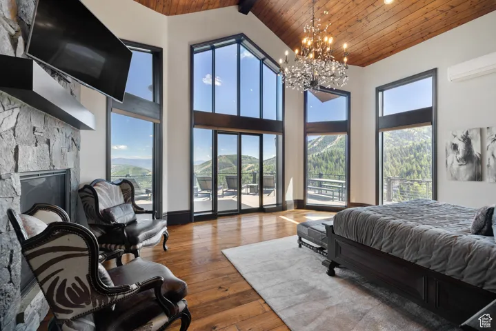 Bedroom featuring wooden ceiling, hardwood / wood-style floors, high vaulted ceiling, a fireplace, and a chandelier