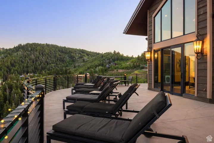 Wooden deck featuring a patio area, a mountain view, and a wooded view