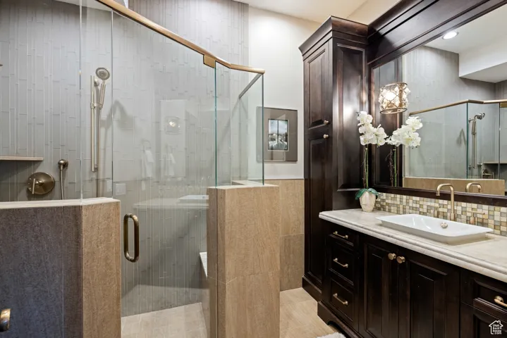 Bathroom featuring vanity, a stall shower, and decorative backsplash