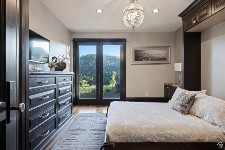 Bedroom featuring dark wood-type flooring, recessed lighting, access to outside, and a chandelier